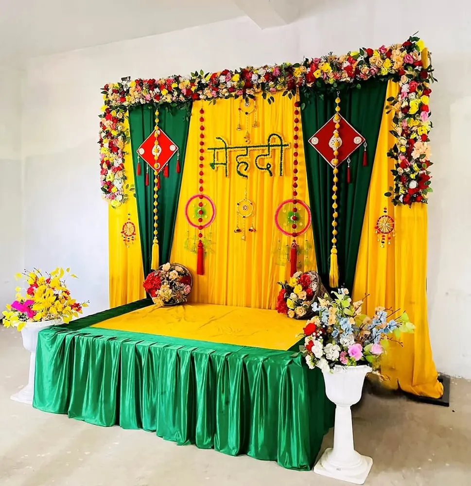 Mehndi ceremony stage decoration with yellow and green drapes, flower frame and hanging decor in Patna